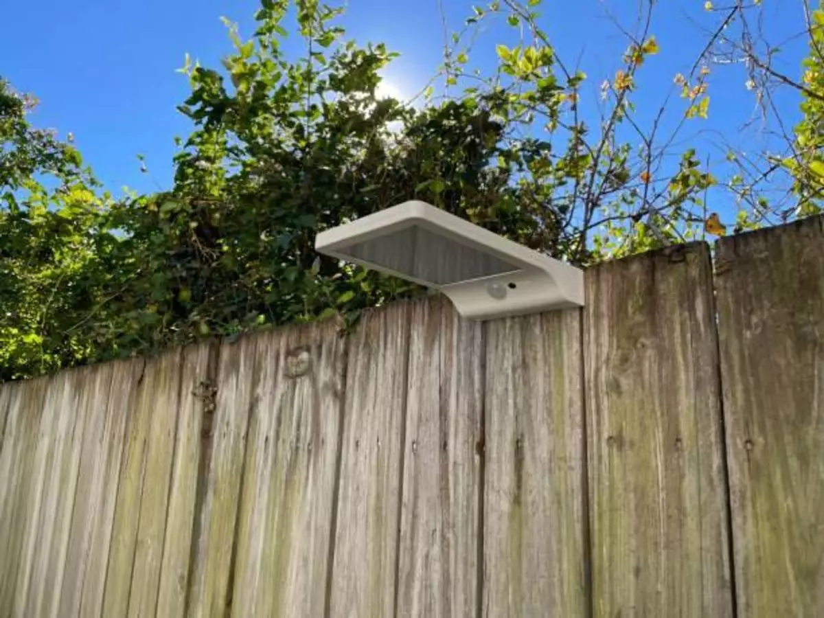 Wall-mounted solar lights being attached to a fence